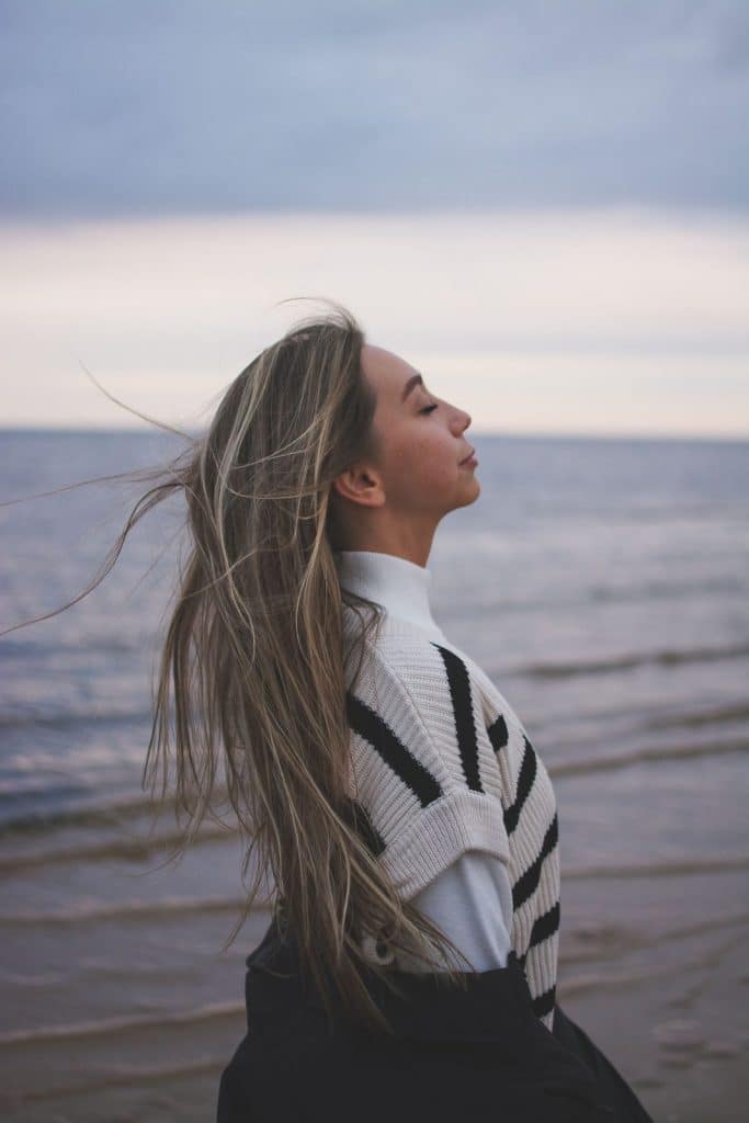 Femme de profil respirant face à la mer