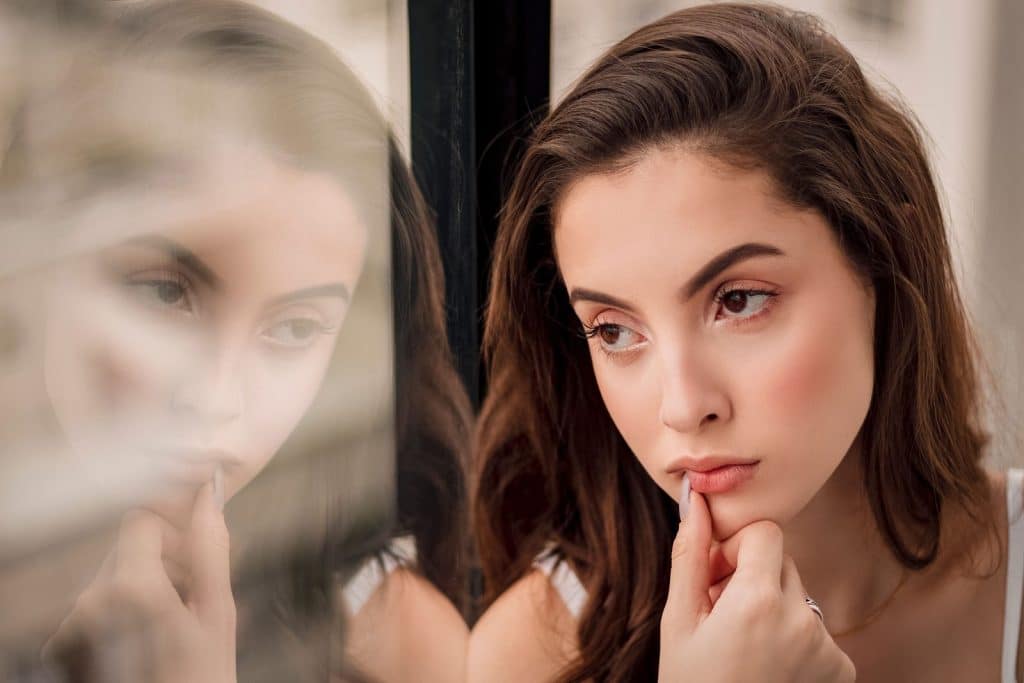 Femme pensive et son reflet dans une vitre